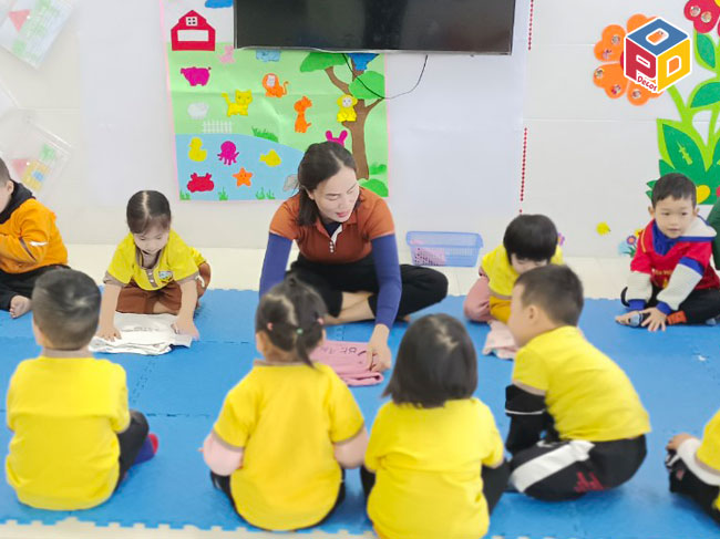 Cô hướng dẫn trẻ gấp quần áo.